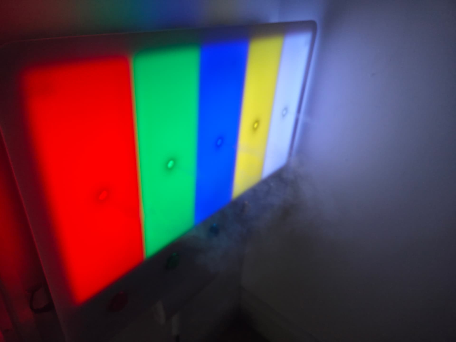 A wall-mounted colour-changing light panel glowing in red, green, blue, yellow and white